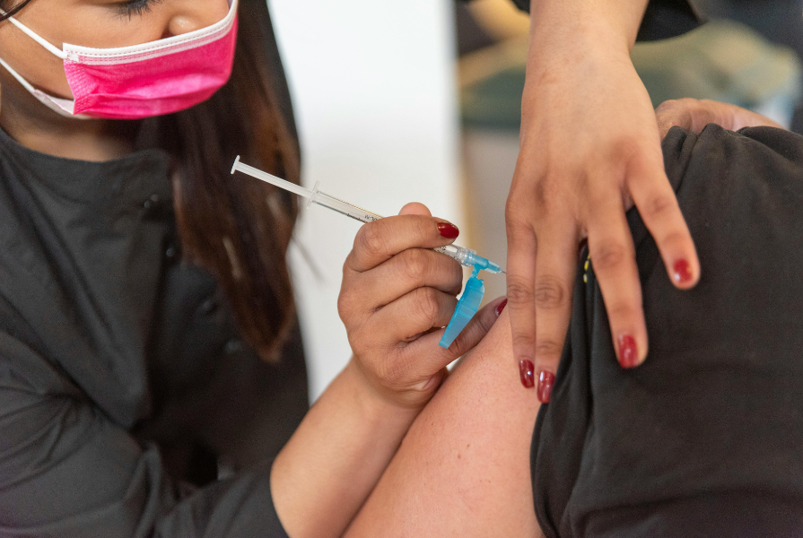 A woman inserting a needle in an arm.