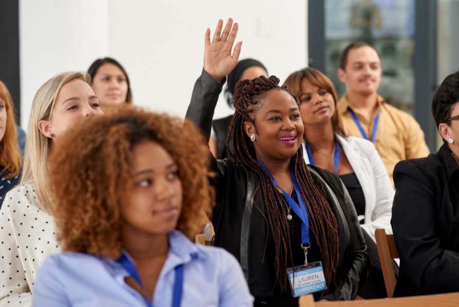 People sitting in a room with woman with her hand raised.
